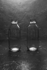 Two empty small glass bottles on a black background. Minimalism.