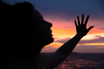 Dark silhouette of a woman on a background of a beautiful sunset sky. Ocean, sunset, man’s power.