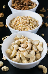 superfood concept, cedar, walnuts, cashew nuts in a plate on a black background