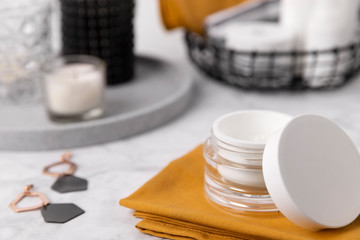 Cosmetic bottle containers with yellow towels and accessories on marble table