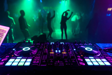 music controller DJ in the booth on the background of the dance floor