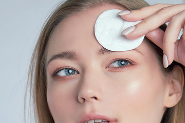 Healthy fresh girl removing makeup from her face with cotton pad. woman with a sponge wihte background cotton pad problem skin.