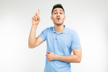 Fototapeta premium surprised man in a blue t-shirt offers an idea showing thumb up on a white isolated background