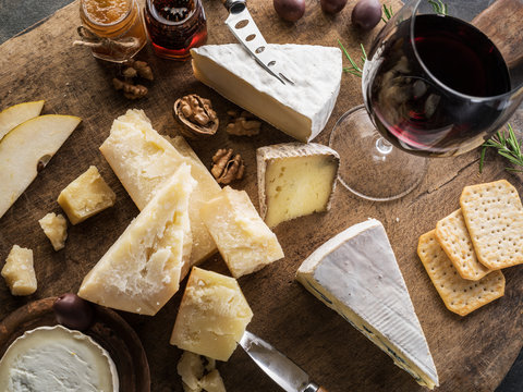 Cheese platter with different cheeses, fruits, nuts and wine on stone background. Top view. Tasty cheese starter.