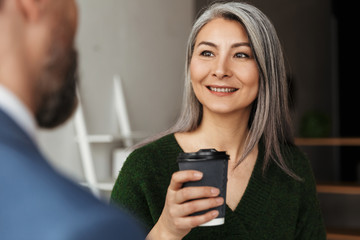 Photo of smiling colleagues discussing project and drinking coffee