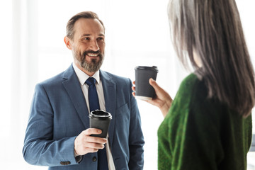 Photo of smiling colleagues discussing project and drinking coffee