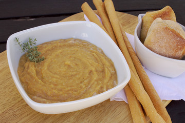 Vegetables soup with bread and baked bread on wooden table with natural light