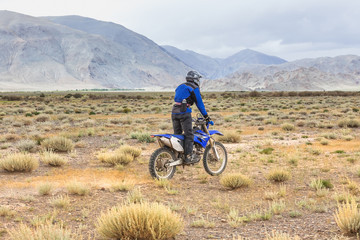 Obraz premium Man riding a motorcross bike in the steppes of Mongolia, on the hills of Mongolia
