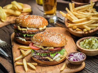 Hamburgers and French fries on the wooden tray.