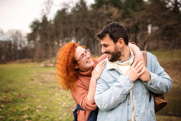 couple on a field trip. a joint journey of two young people. Girl with orange hair is having fun in the woods with a guy who has a beard