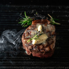 A steaming beef tenderloin steak is grilled in a grill pan with the text copy space. The concept of...