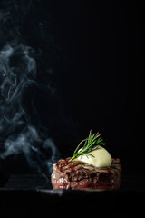 Cooking beef tenderloin steak on a grill pan on a black dark background with the text copy space. The concept of the recipe, filet Mignon