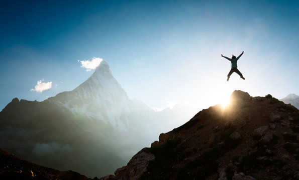 Woman full of joy jumping up on top of the mountain