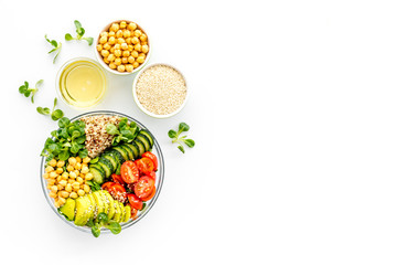 Healhty vegan lunch bowl. Avocado, quinoa, sweet potato, tomato, spinach and chickpeas vegetables salad on white table. Top view