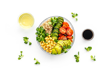 Healhty vegan lunch bowl. Avocado, quinoa, sweet potato, tomato, spinach and chickpeas vegetables salad on white table. Top view