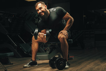 Fototapeta na wymiar Male with sport body lifting dumbbells at the gym
