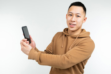 Asian guy shows a smartphone in his hand on a white background