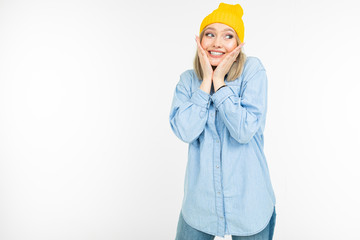 blond charming girl in a casual look with a denim shirt hugs herself on a white background