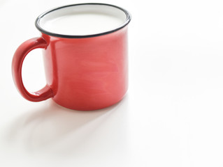 red mug with milk on a white background
