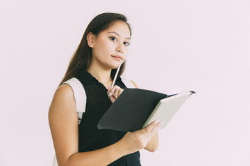 Serious pensive student girl reading her notes, holding pen and open notebook. Young Latin woman standing isolated over white background. Learning concept