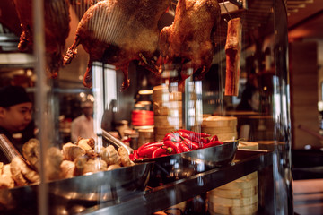 Showcase of a Chinese street restaurant with traditional Chinese food and products, cook behind glass
