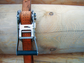 Fastening belt with tensioner. Peeled logs in a horizontal position. Wood transportation concept.
