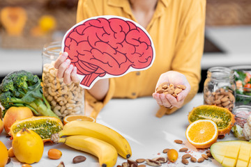 Holding human brain model with variety of healthy fresh food on the table. Concept of balanced nutrition for brain health