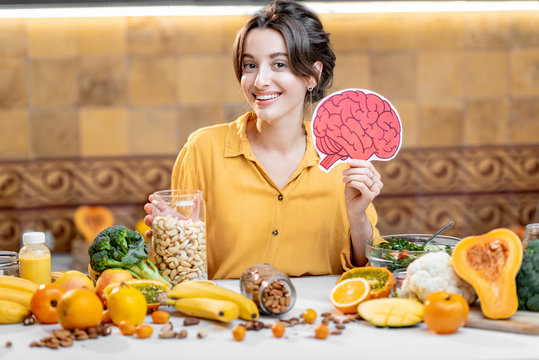 Woman holding human brain model with variety of healthy fresh food on the table. Concept of balanced nutrition for brain health