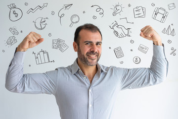 Latin man showing his biceps with hand drawn business sketches. Cheerful powerful handsome businessman looking at camera. Jolly confident middle-aged man flexing biceps. I can do it concept