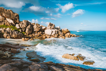 Obraz na płótnie Canvas Grand L Anse, La Digue, Seychelles. Tropical coastline with hidden beach, unique granite rocks and lonely sail boat in ocean