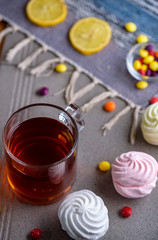 cup of tea with sweets and marshmallow on a gray background