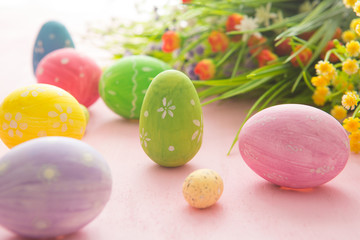 Fototapeta na wymiar Easter eggs with wild flowers on a wooden pink table background
