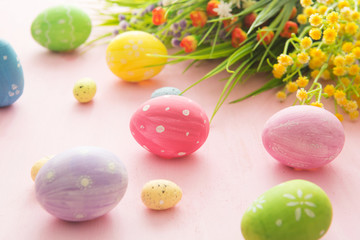 Easter eggs with wild flowers on a wooden pink table background