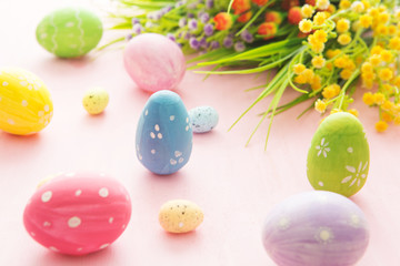 Fototapeta na wymiar Easter eggs with wild flowers on a wooden pink table background