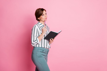 Portrait of minded curious girl hold copybook want write essay think thoughts ponder look copy space wear stylish clothing isolated over pink color background