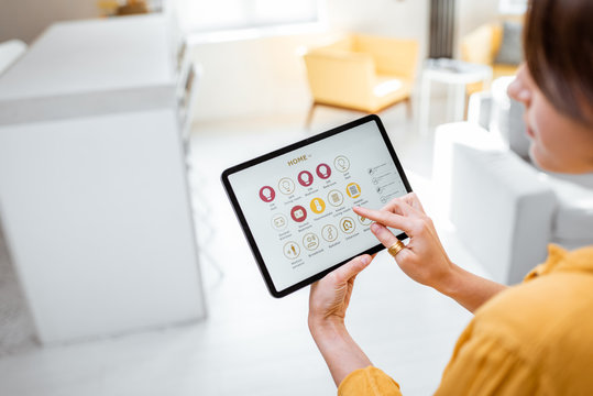 Woman controlling smart home devices using a digital tablet with launched application. Smart home concept