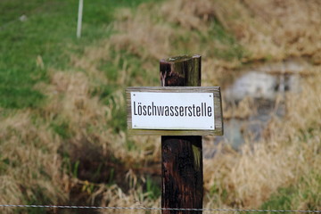 Fire water tapping point on the lawn. Sign in german. Selected focus.