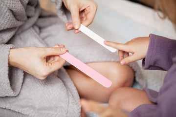 Girl makes manicure mother, at home in bed