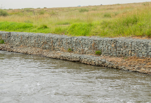 Gabion retaining walls to control erosion and flooding on the banks of a fast flowing river