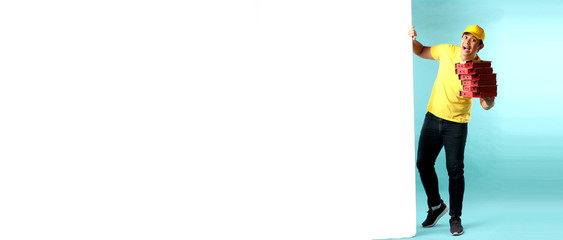 full body Asian man Pizza delivery courier in yellow uniform  pulling big white board,on blue background in studio With copy space.