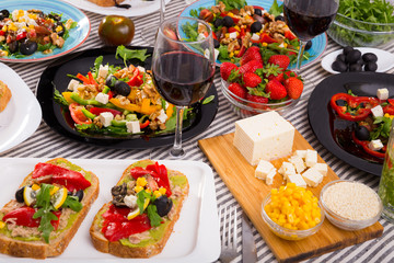 Many plates with different vegetarian food and  glass of wine