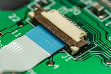 Macro photo of a flat ribbon cable and connector on a green printed circuit board (PCB)