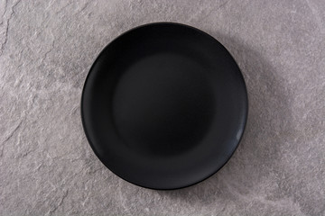 Empty black plate on gray background top view