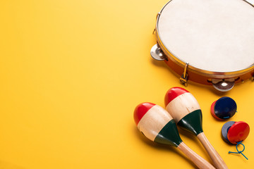 Wooden colorful maracas with tambourine and castanets on yellow background - obrazy, fototapety, plakaty