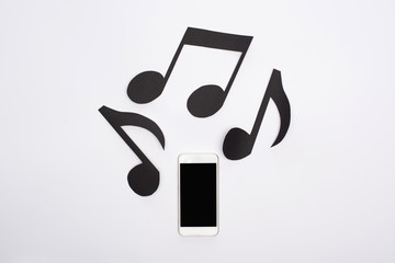 Top view of music paper cut notes and smartphone on white background