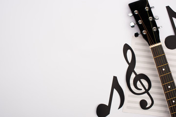 Top view of paper cut notes, music book and acoustic guitar on white background