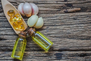 Garlic oil in small bottles and capsule, stethoscope, books on wooden table.