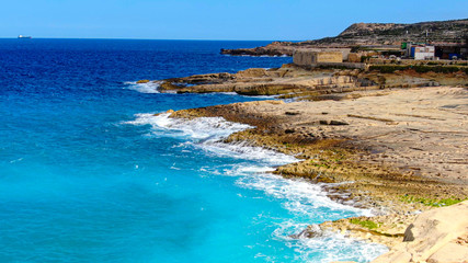 Wonderful turqouise blue ocean water hitting against the rocks - top down view - aerial photography