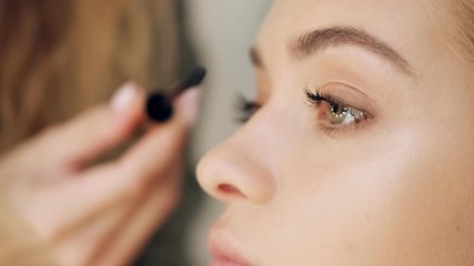 A close-up view of woman's eyes while professional makeup artist is applying mascara at a beauty salon