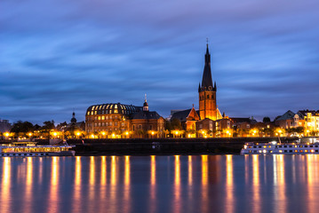 Obraz premium Cruise ship in the river and Saint Lambertus Catholic Church; night view of Dusseldorf on the bank of Rhine in Germany